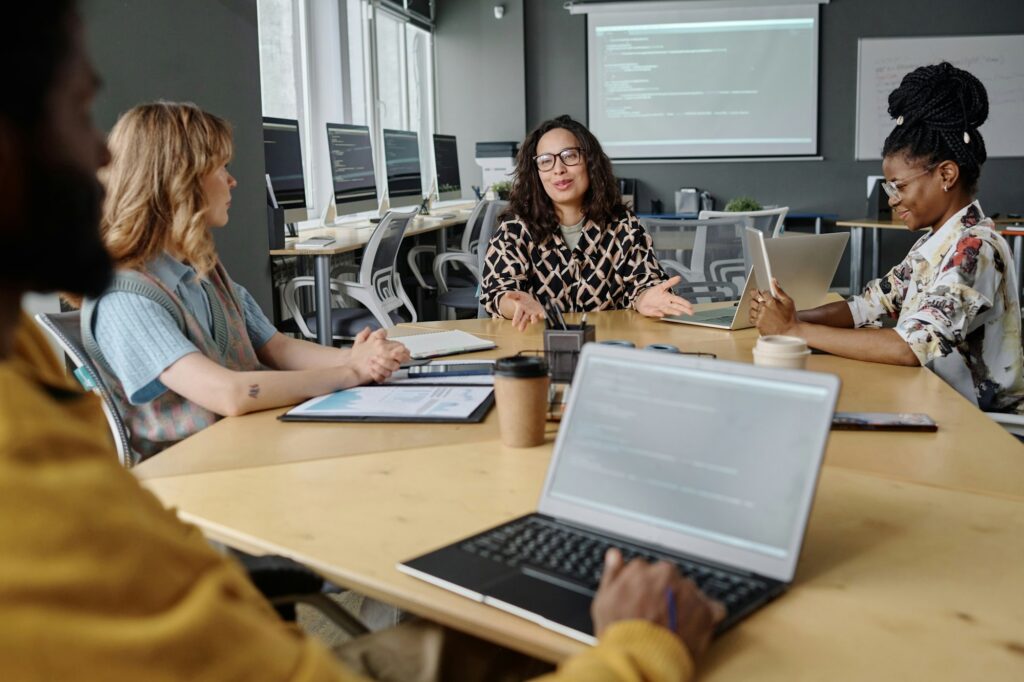 Young Colleagues Discussing IT Project Sitting at Table in Office