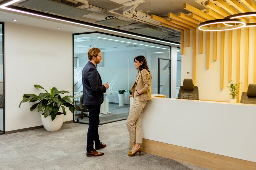 Professional Colleagues Engage in Conversation by the Reception in a Modern Office Setting