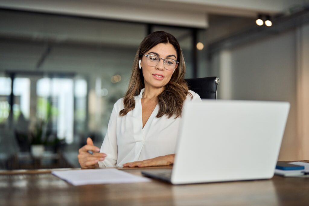 Mid aged business woman manager having hybrid meeting working in office.